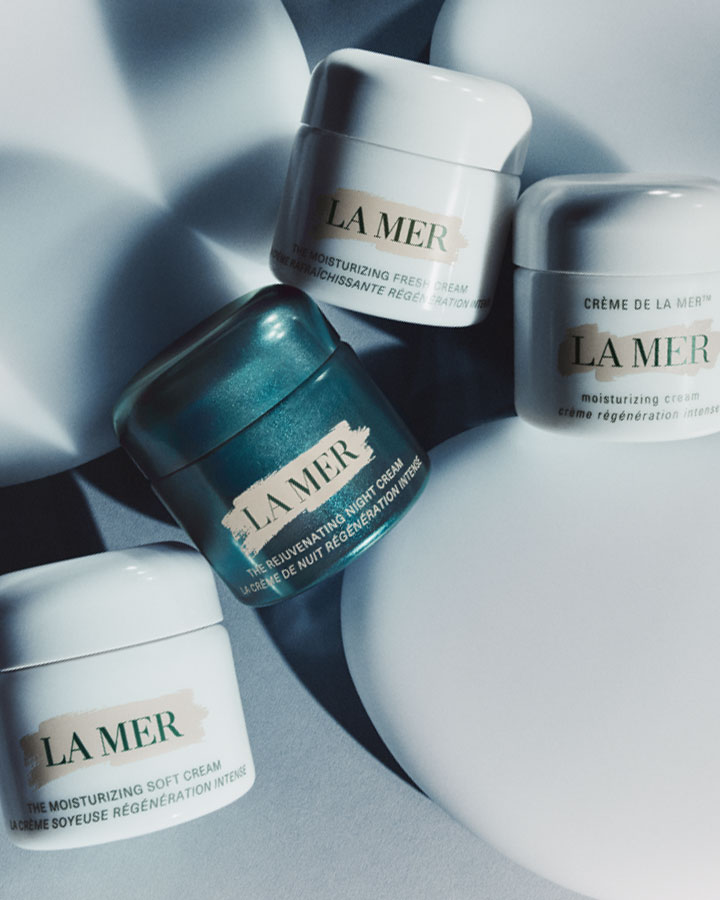 Collection of La Mer moisturisers dynamically resting on stone spheres in dramatic lighting